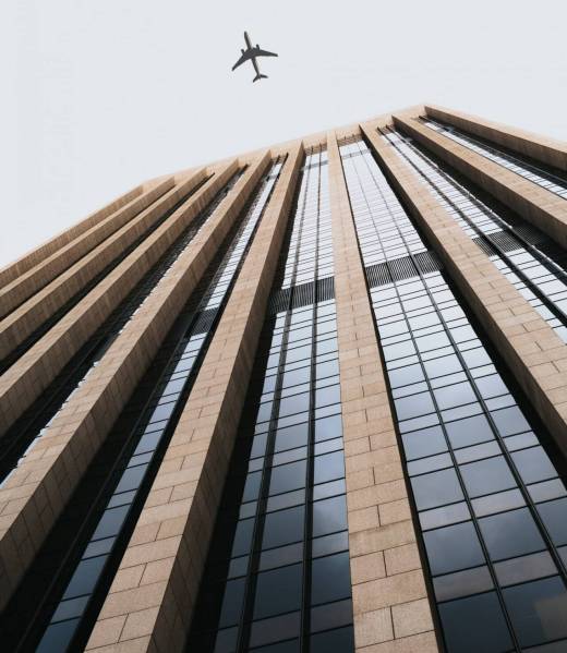 hermoso-tiro-angulo-edificio-alto-negocios-avion-volando-encima_181624-1592